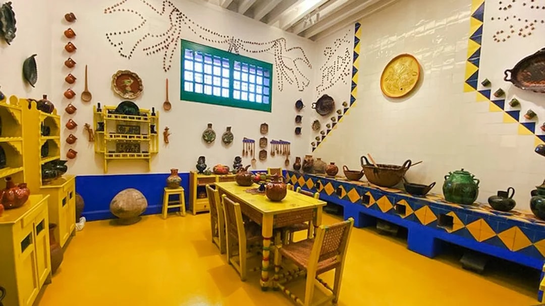 Frida Kahlo Museum kitchen with yellow furniture and traditional Mexican pottery.