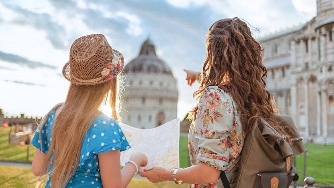 Tour guide explaining Pisa Baptistery to a girl holding a map in Pisa, Italy.