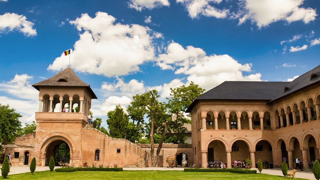 Mogosoaia Palace courtyard with arched brick architecture under a blue sky.