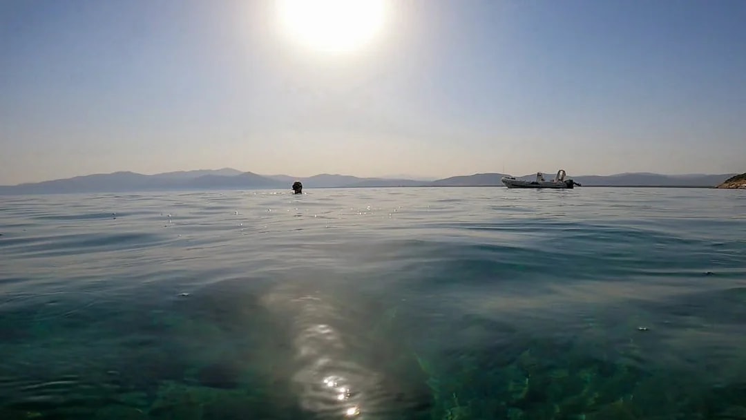 Snorkeling in clear waters with a boat in Nea Makri, Athens under the sun.