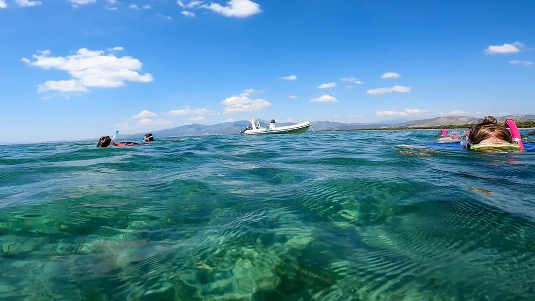 Snorkelers in clear waters near a boat in Nea Makri, Athens.
