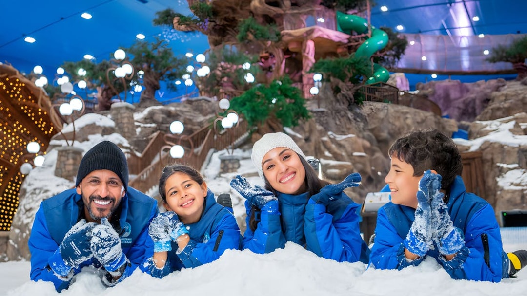 Family enjoying snow activities at Snow Abu Dhabi indoor park.