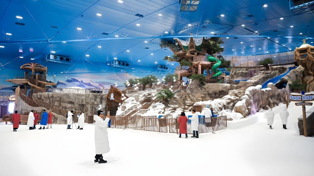 Visitors exploring Snow Abu Dhabi's indoor snow park with slides and snowy landscapes.