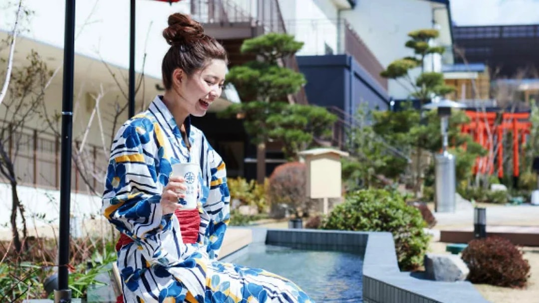Person in yukata enjoying foot bath at Solaniwa Onsen, Japan.
