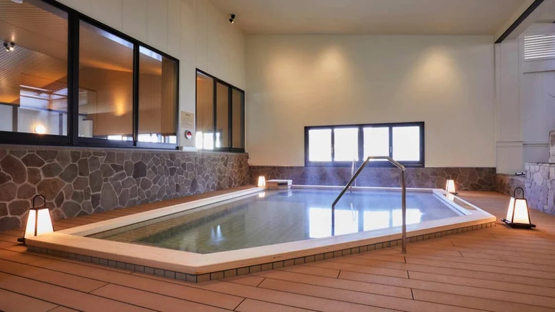 Indoor hot spring bath at Solaniwa Onsen, Osaka, with stone walls and ambient lighting.