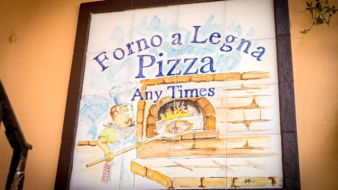 Wood-fired pizza oven sign in Capri, Italy, featuring a chef with a pizza paddle.