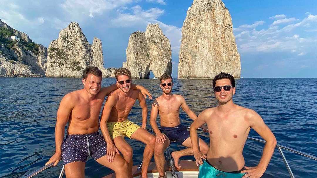 Boat tour near Faraglioni rocks, Capri, with group enjoying the view.