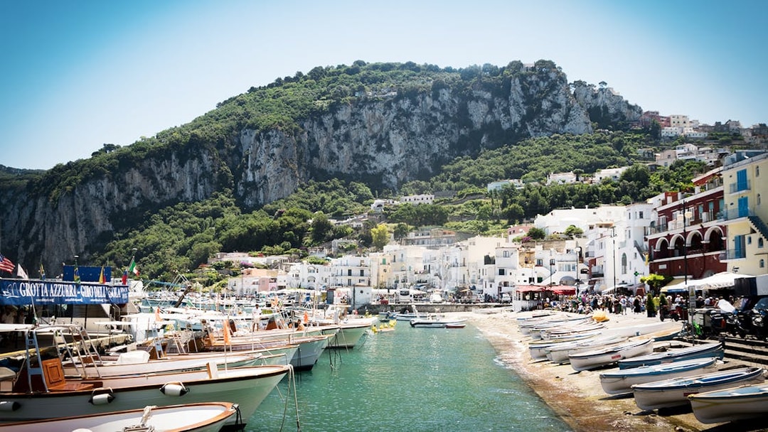 Boats docked at Marina Grande, Capri with cliffs and hillside buildings in the background.