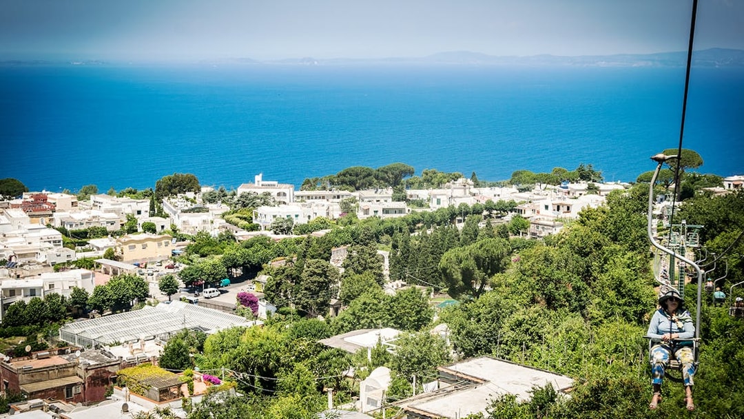Chairlift view over Anacapri with lush greenery and the sea, part of Capri & Anacapri tour from Sorrento.