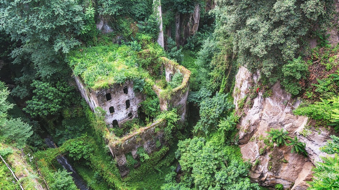 Abandoned mill ruins covered in greenery in Sorrento, Italy.