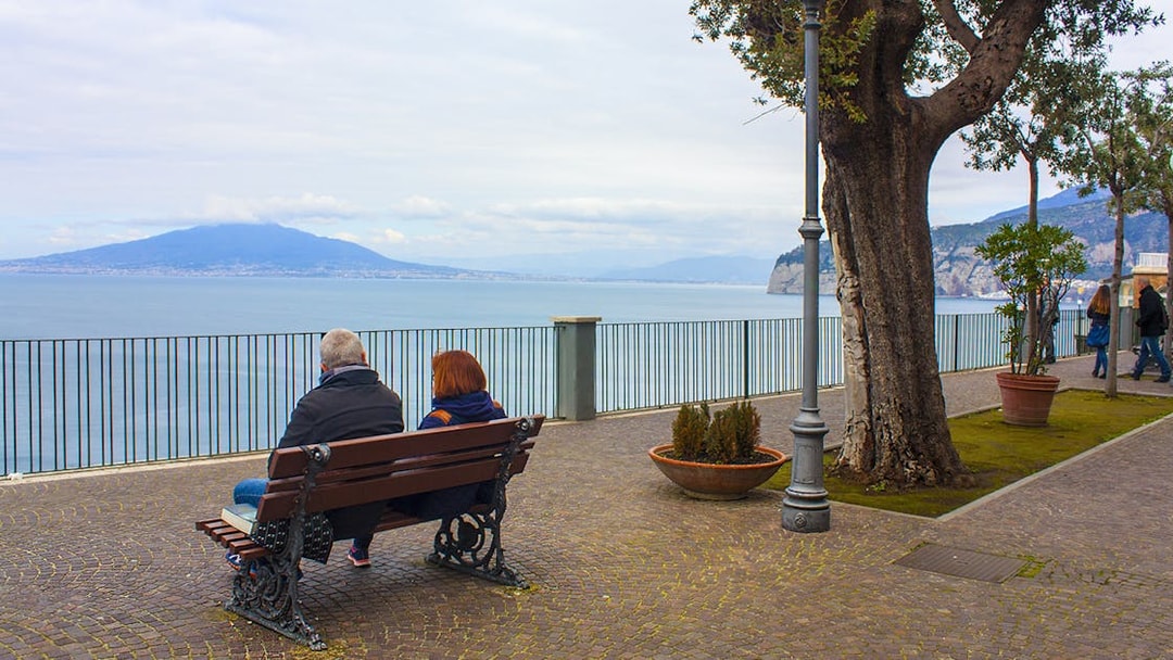 Couple sitting on a bench overlooking the sea and Mount Vesuvius in Sorrento.