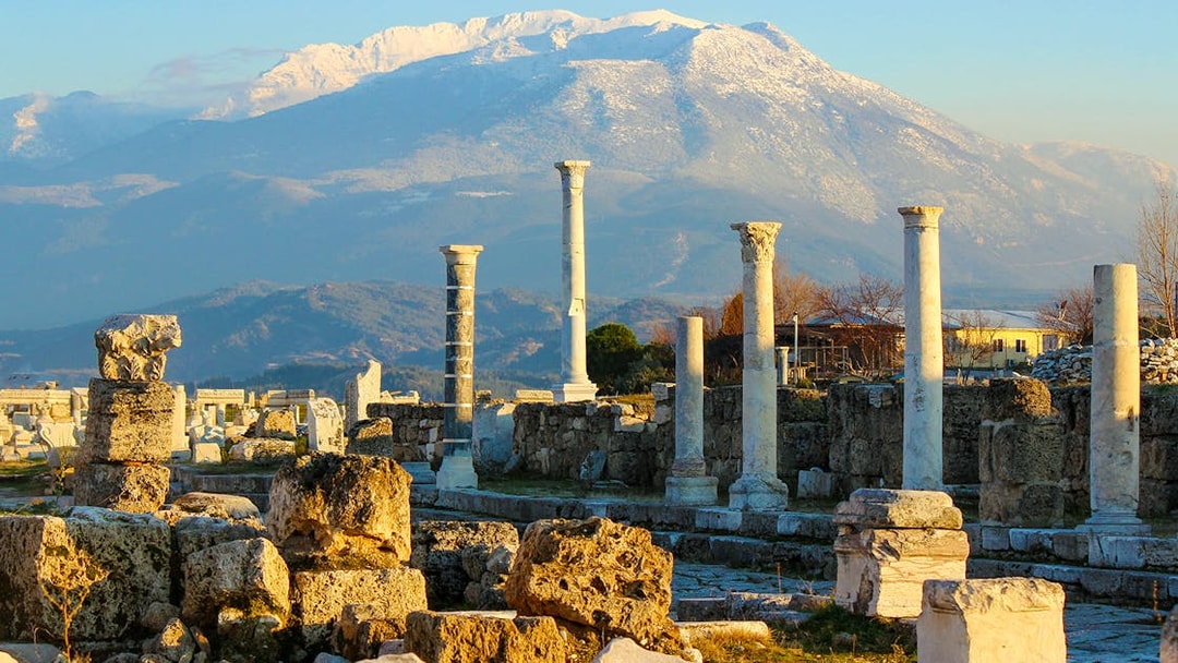 Ancient ruins with stone columns and mountain backdrop in Pompeii, Italy.