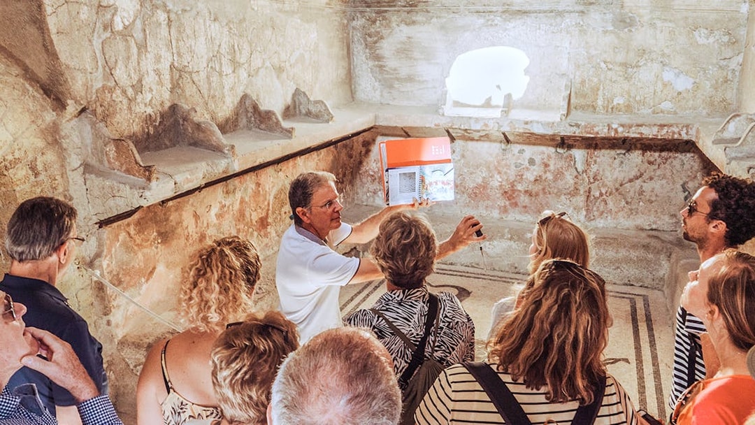Guide explaining ancient ruins to a group of tourists in Pompeii, Italy.