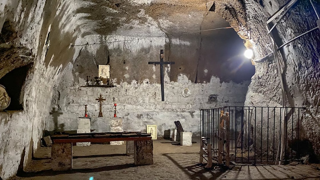 Underground chapel in Naples with stone altar, crosses, and religious icons.