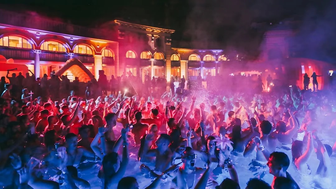 Crowd enjoying Sparty bath party at night in Budapest thermal baths.