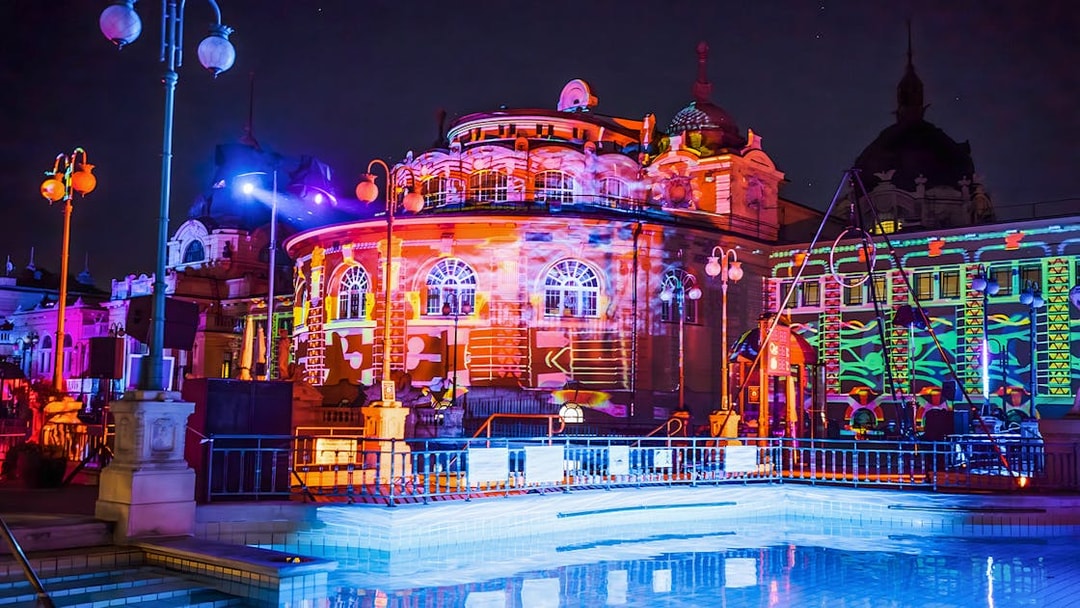 Colorful lights illuminate the Széchenyi Thermal Bath during a Sparty in Budapest.