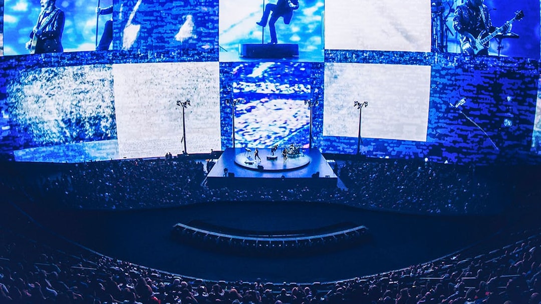Concert at Sphere Las Vegas with band performing on stage, immersive visuals surrounding audience.