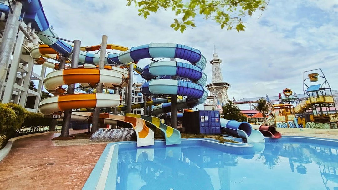 Colorful water slides at Splash Out Langkawi Water Theme Park, Malaysia, with a pool and tower in view.