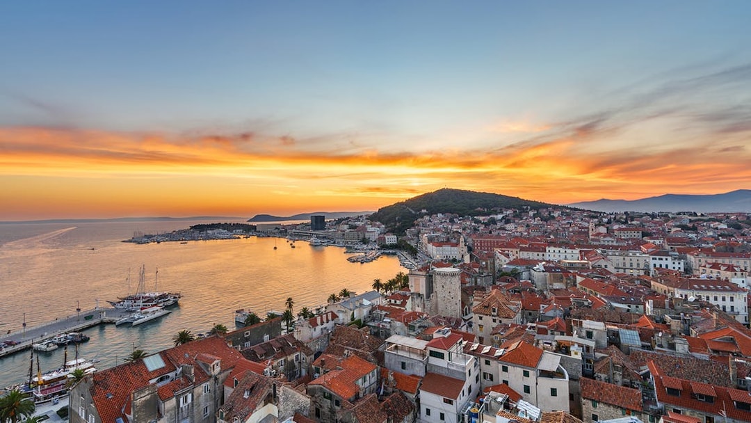 Sunset view of Split Riviera with boats docked, highlighting the coastal cityscape.
