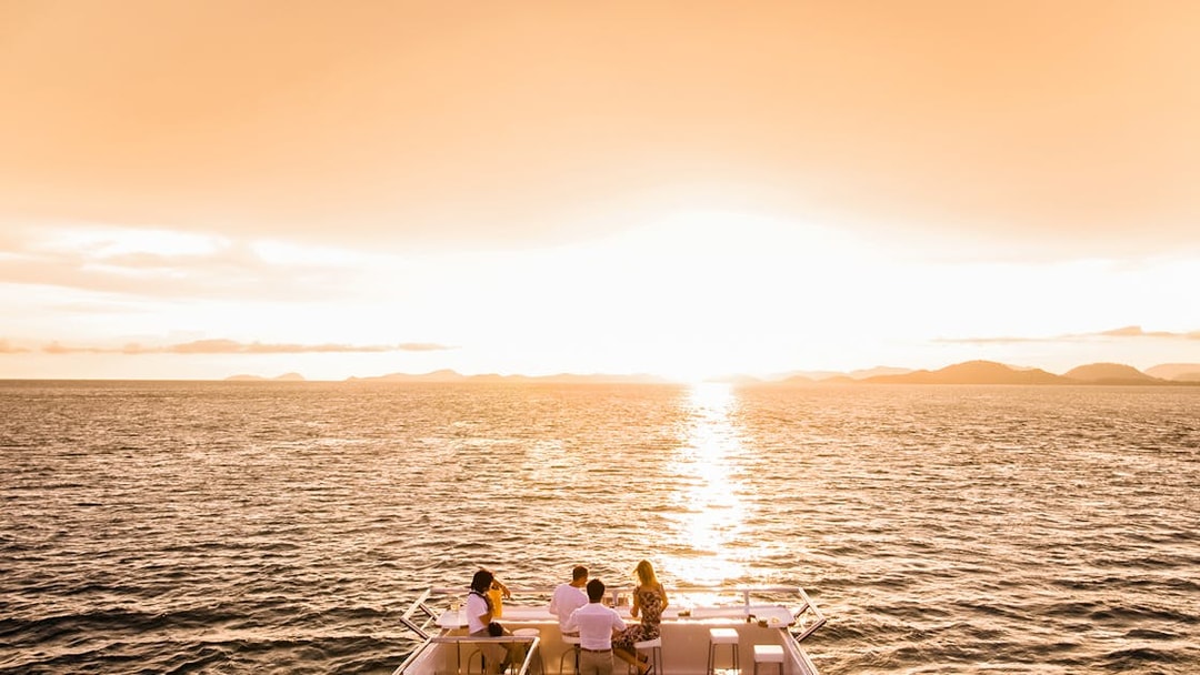 Sunset view from a boat on Split Riviera cruise with people enjoying drinks.