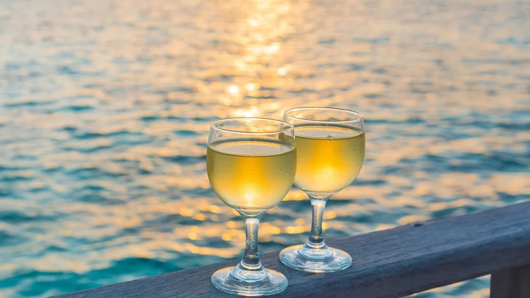 Two wine glasses on a railing with a sunset over the sea in Split, Croatia.