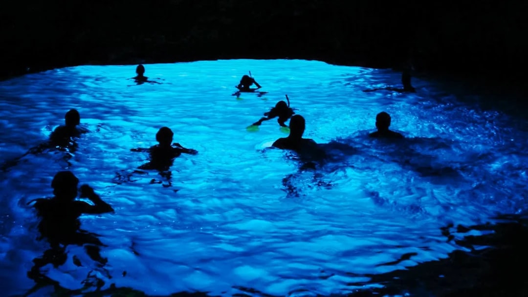 Snorkelers exploring the illuminated Blue Cave in Croatia.