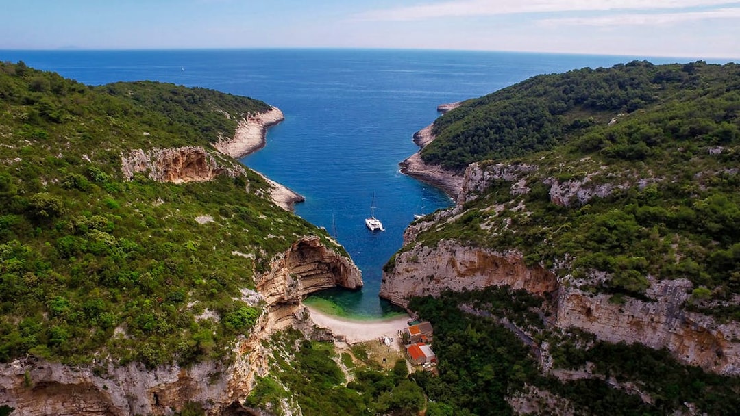 Aerial view of secluded cove with yachts, part of 5 Islands Hopping Tour with Blue Cave visit.