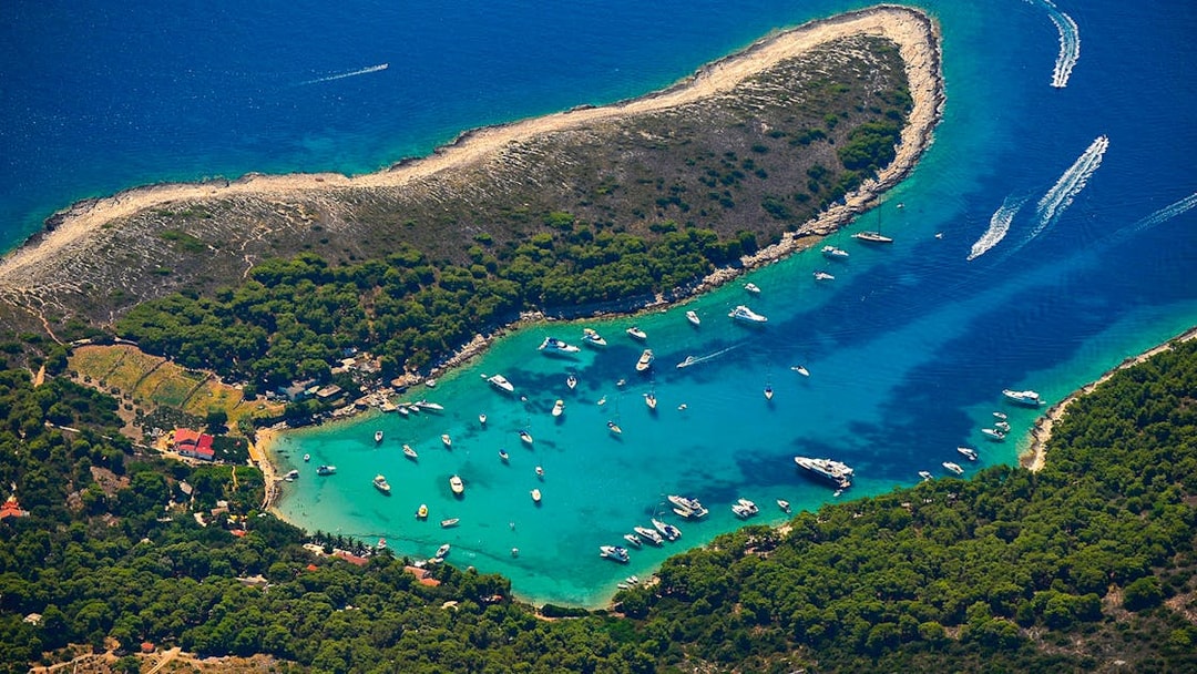 Aerial view of boats in a turquoise bay surrounded by lush greenery on a 5 Islands Hopping tour.
