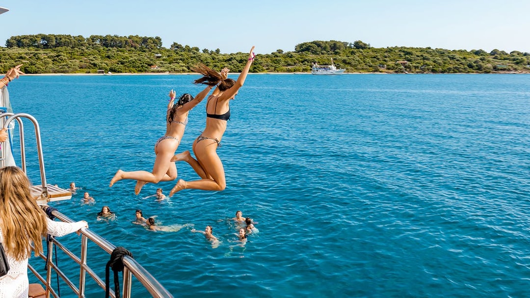 Girls jumping off boat deck into Blue Lagoon during Split, Croatia party.
