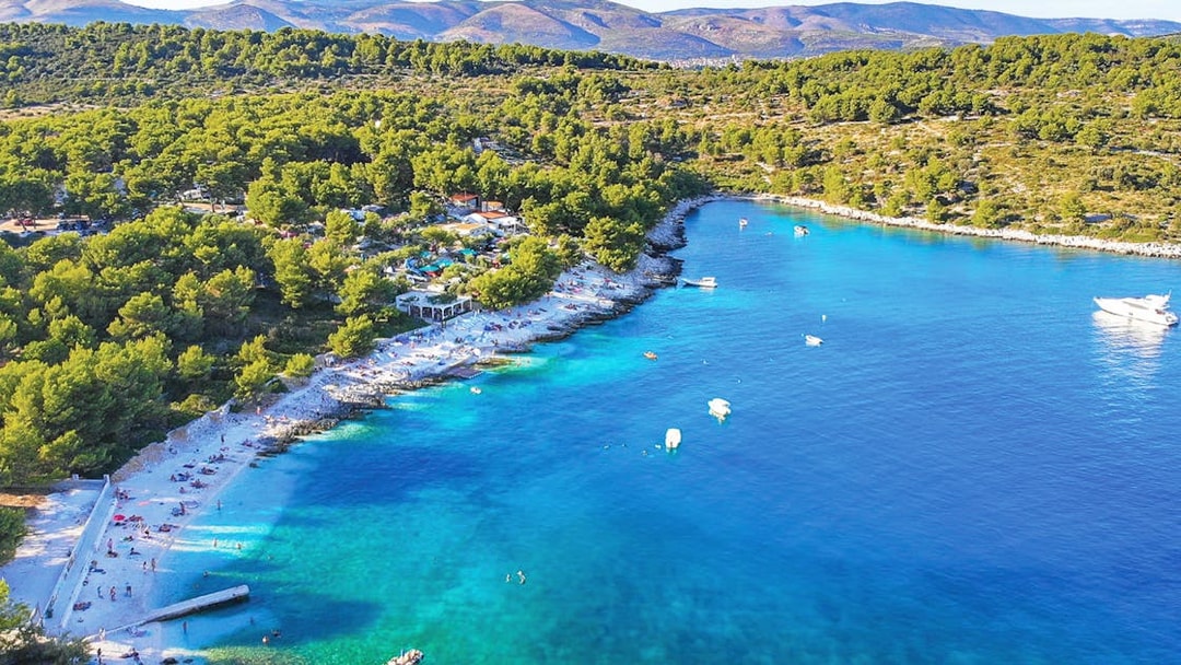 Aerial view of Duga Bay with turquoise waters, boats, and a forested coastline.