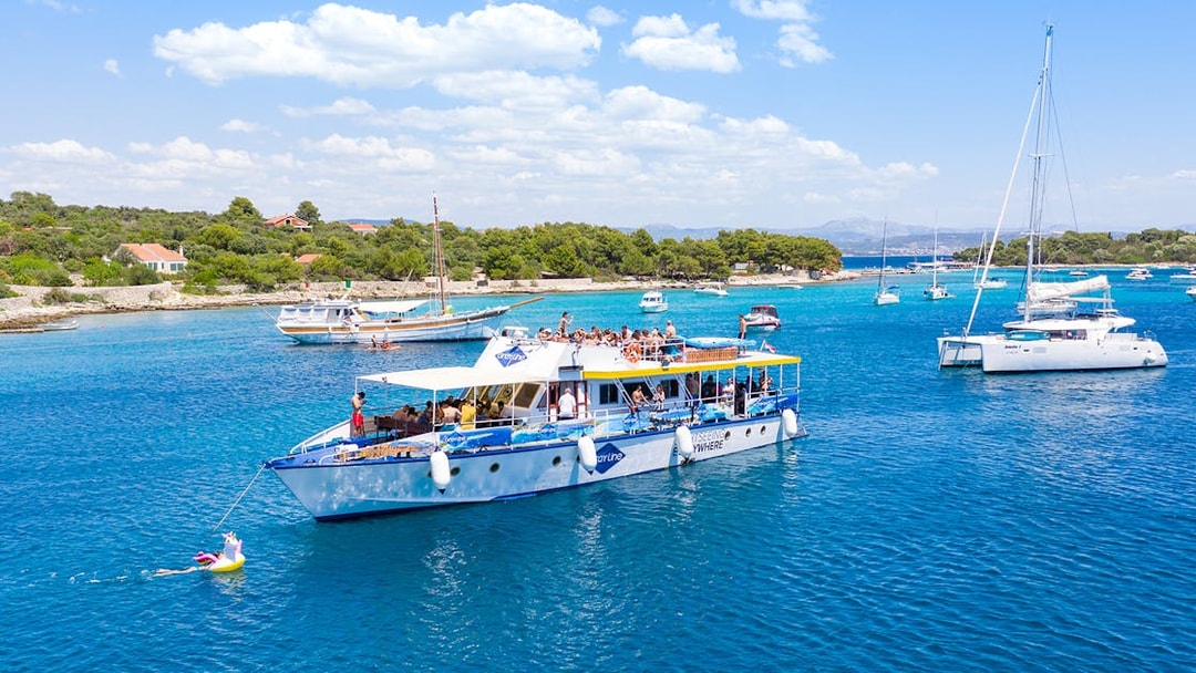 Cruise ship with tourists in Split's Blue Lagoon, surrounded by sailboats and clear blue water.