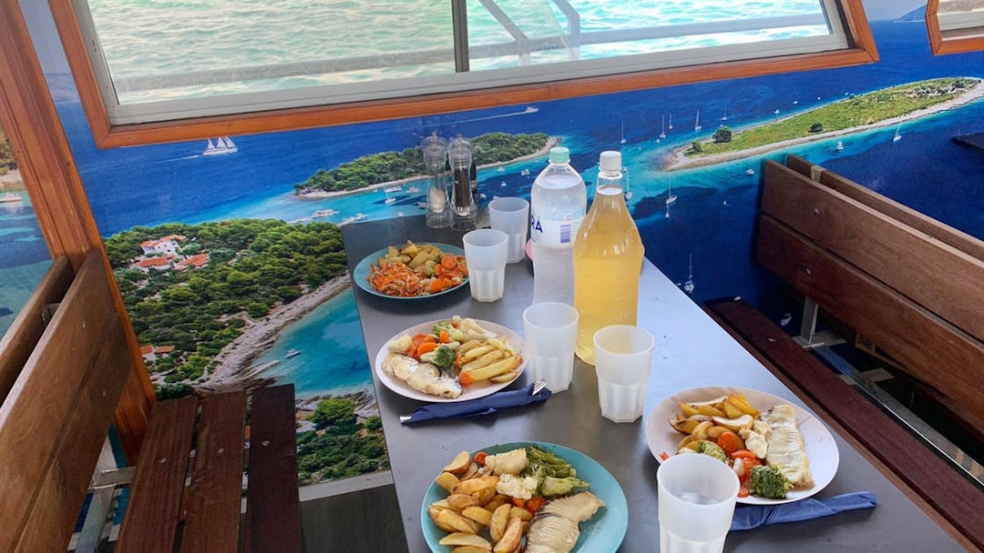 Lunch setup on a cruise with plates of fish and vegetables, Split Blue Lagoon tour.