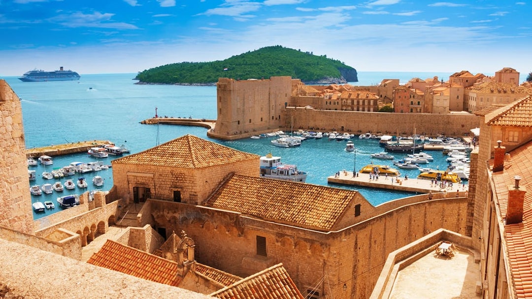 Old town harbor with boats and cruise ship in Dubrovnik, Croatia, viewed from city walls.