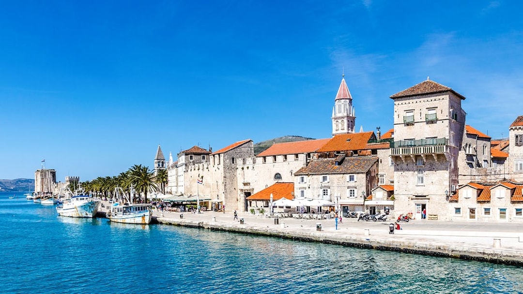 Seafront promenade with historic fortress and boats in Trogir, Croatia.