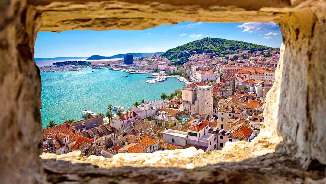 View of Split, Croatia from a stone window, featuring the coastline and historic buildings.