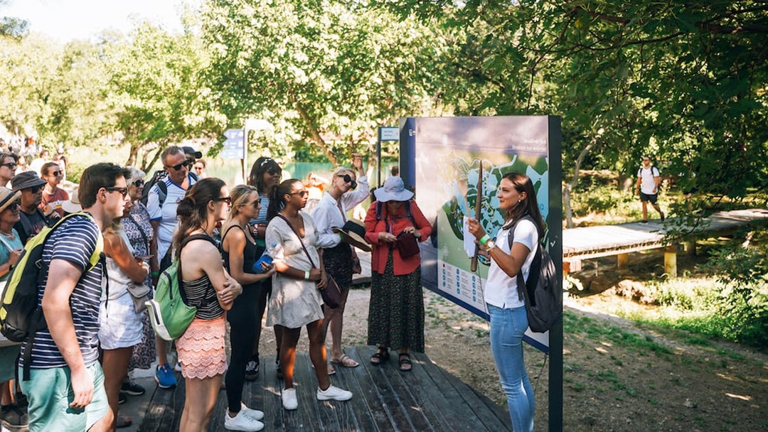 Tour group listening to a guide at Krka National Park during a Split wine tasting trip.