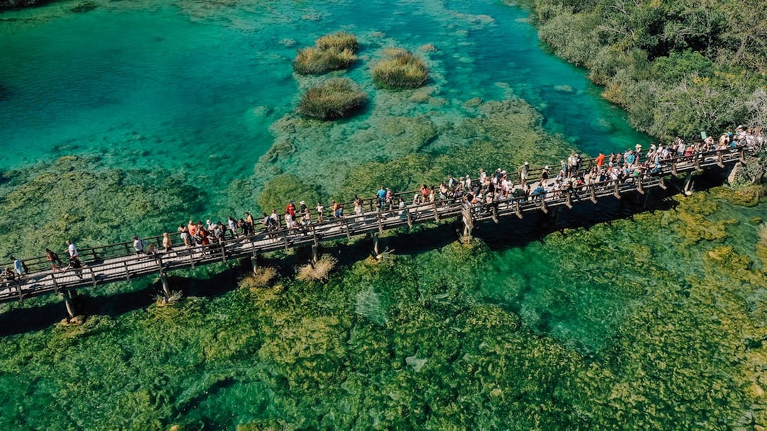 Visitors on a wooden bridge over turquoise waters at Krka National Park, Croatia.