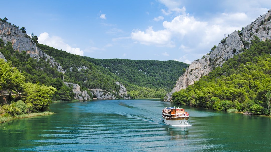 Boat cruising through Krka National Park's lush canyon, Croatia.