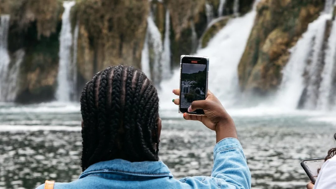 Visitor photographing waterfalls at Krka National Park during tour from Split.
