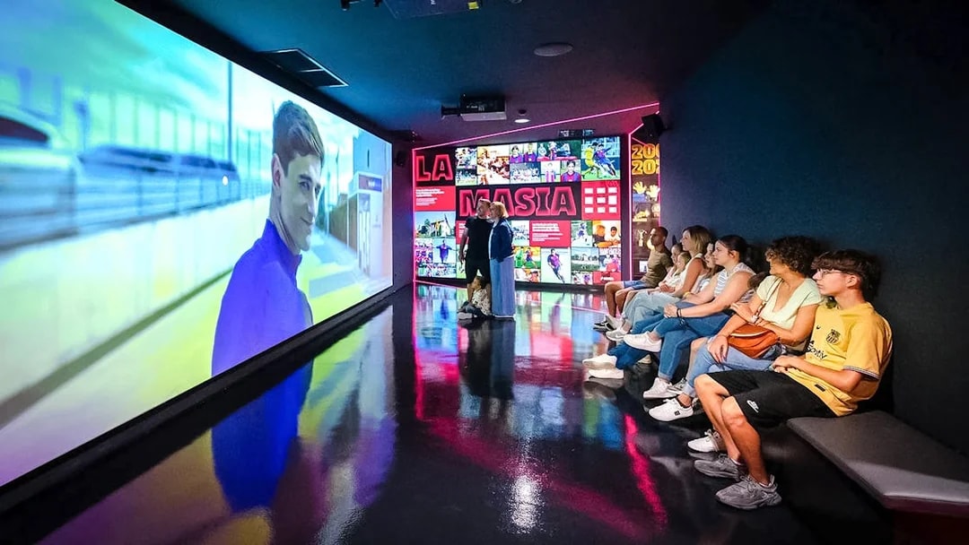 Visitors watching a video at La Masia exhibit in Spotify Camp Nou Barça Museum.
