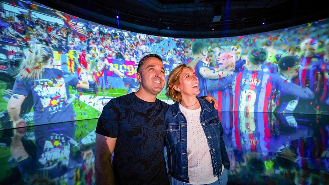 Couple enjoying interactive exhibit at Camp Nou Barça Museum.