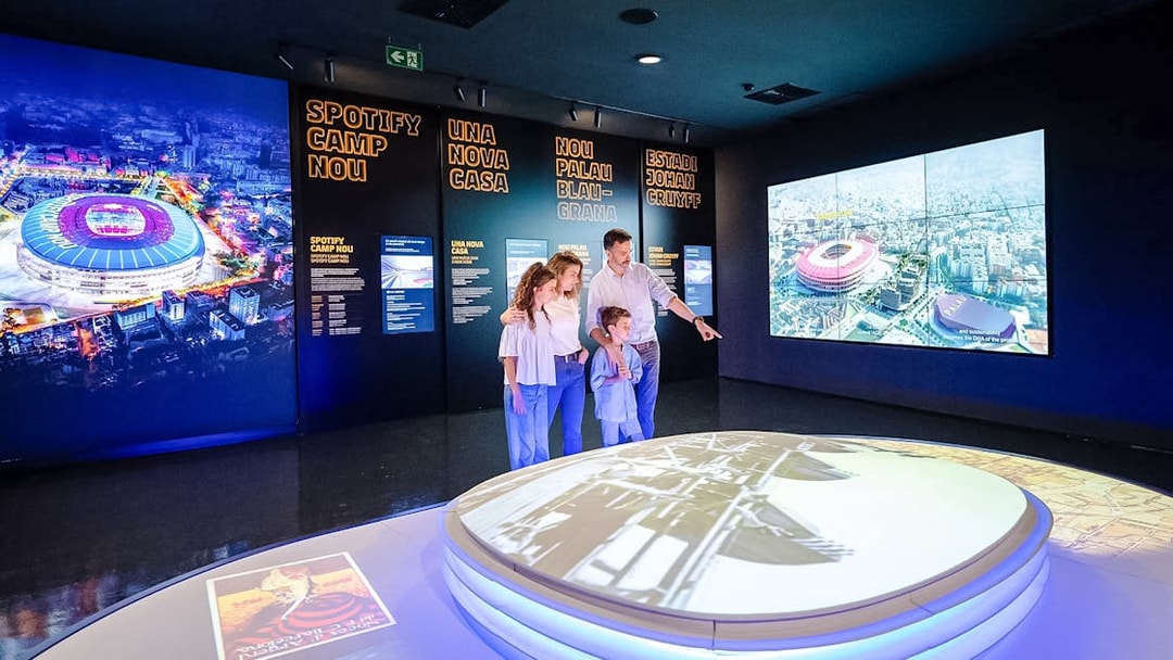Family exploring interactive exhibit at Spotify Camp Nou Barça Museum.