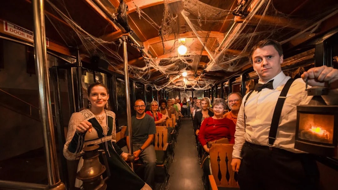 St. Augustine ghost tour participants on a trolley with guides holding lanterns.