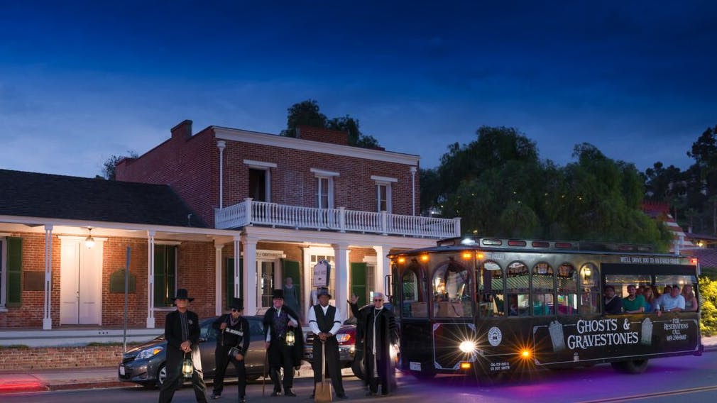 Ghost tour trolley in St. Augustine with guides holding lanterns at night.