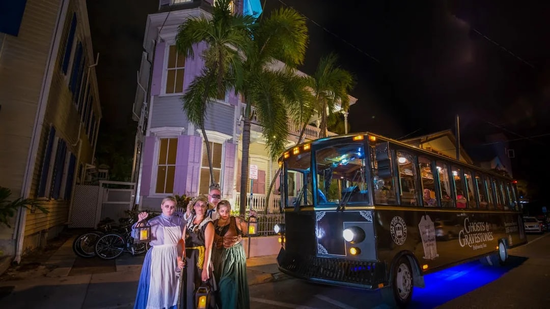 St. Augustine Ghosts & Gravestones tour trolley at night with costumed guides holding lanterns.