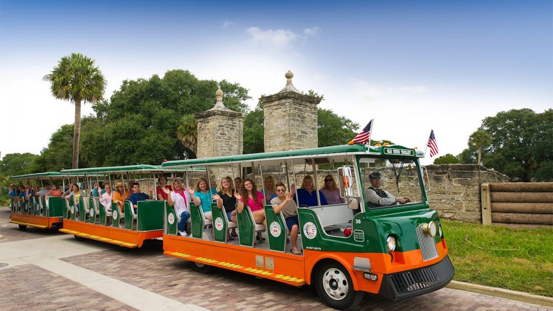 St. Augustine Old Town Trolley with passengers near historic stone gate.