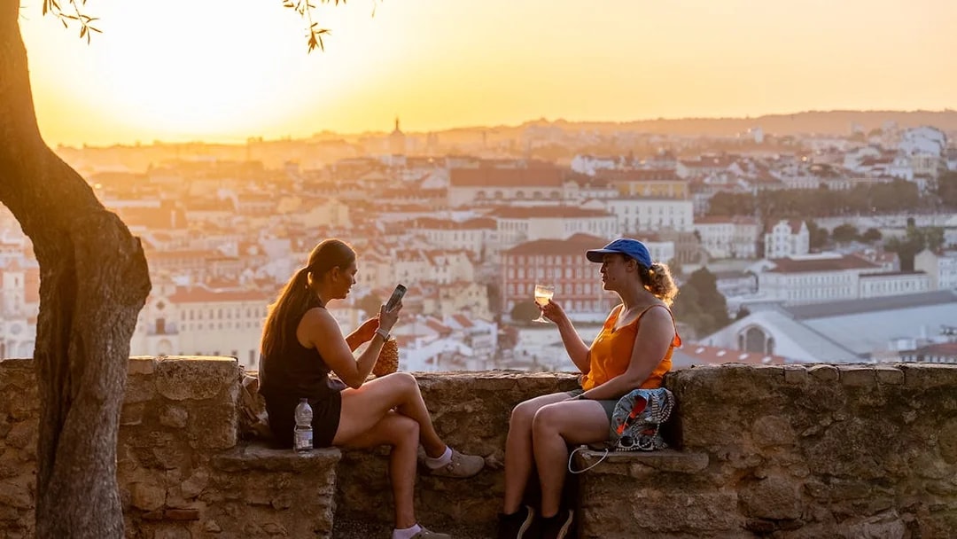 Visitors enjoying wine on St. George’s Castle terrace at sunset, Lisbon.