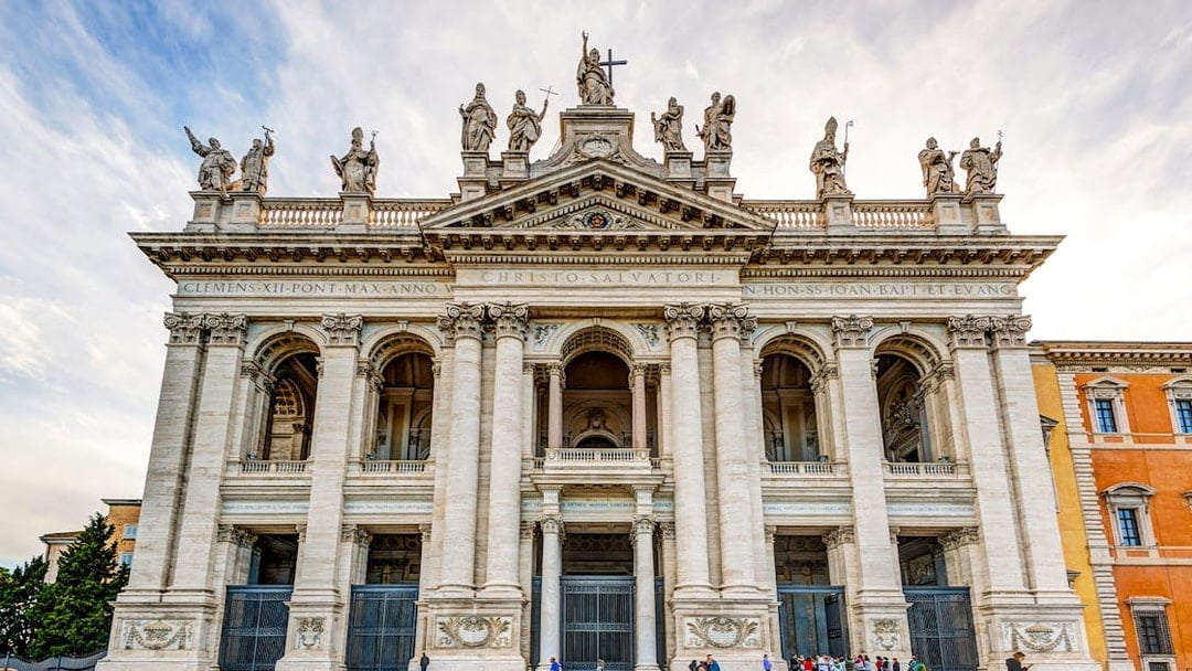 St. John Lateran Basilica facade in Rome with visitors outside.