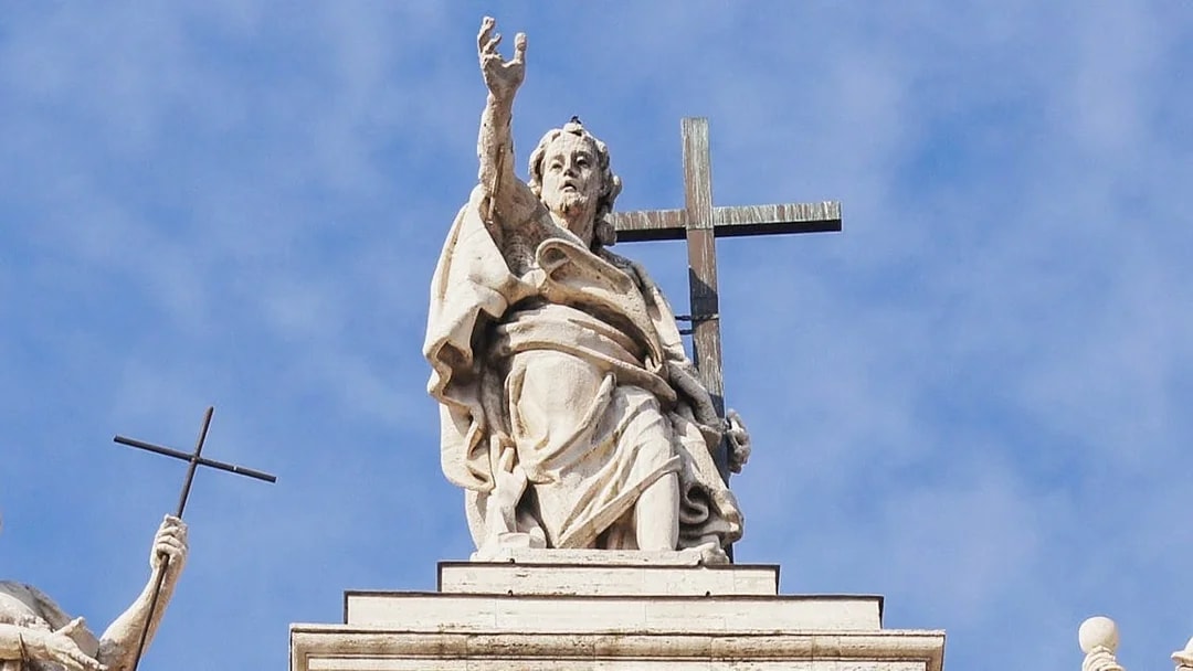 Statue atop St. John Lateran Basilica in Rome holding a cross.