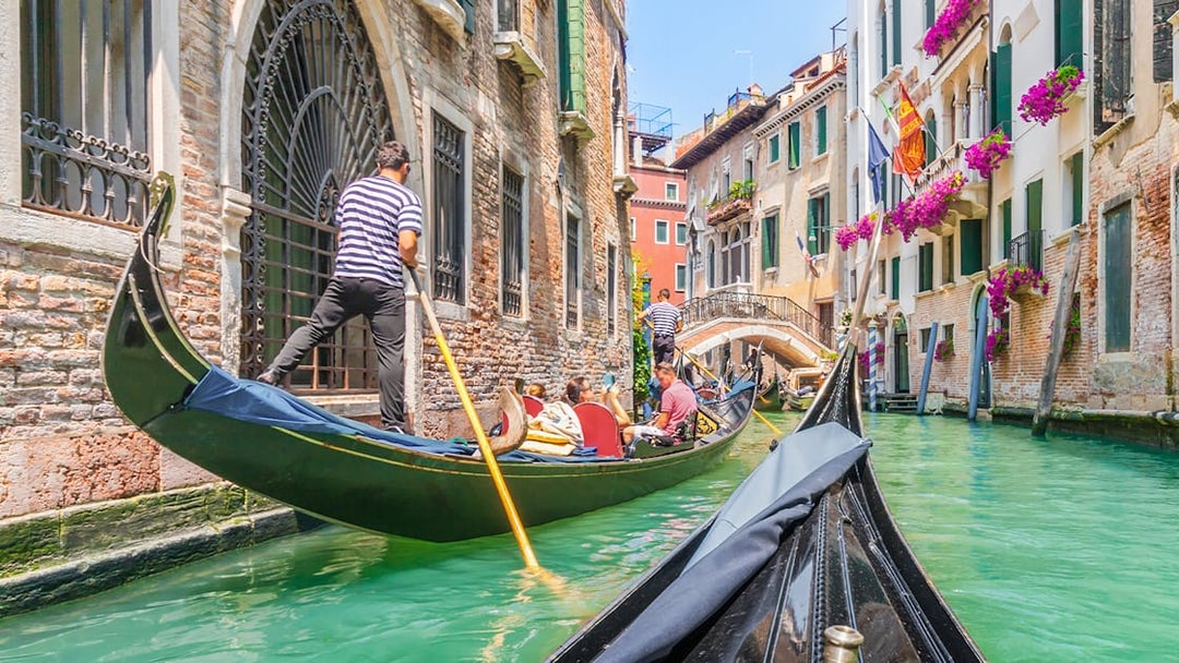 Gondola ride through Venice canal with vibrant buildings and flowers.